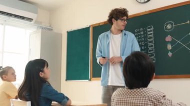 Matematik formülü veya teorisi ile karatahtanın önünde dururken sınıfın etrafına bakan profesyonel akıl hocası. Çeşitli ilköğretim öğrencileri matematik dersinde öğreniyor, çalışıyor ve oturuyor. Pedagoji.