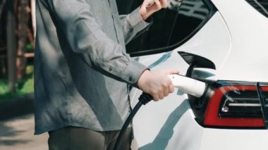 Yavaş çekim adamı, uygulama ekranında elektrikli araba aküsü şarj durumu, menzil ve şarj limitini kontrol ediyor. Akıllı teknoloji aygıtı, EV arabasının araba aküsündeki elektrik depolama verilerini şarj ettiğini gösteriyor..