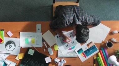 Toplantıda tasarımcı yazma ve logo grafiği tasarlamanın en üst görünümü. Renkli paletler üzerinde çalışan iş adamlarının yakınlaşması ve masaya kağıt ve ekipman ile yapışkan notlar yazmak. Sempozyum.