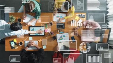 Üst görünüm yöneticisi dizüstü bilgisayarı elinde tutuyor ve yatırımcı dinlerken borsa istatistiksel hologramıyla finansal grafiğini sunuyor. Toplantı odasında oturan müdürün hava görüntüsü. Cemaat.