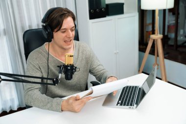 Akıllı yayıncının sunucu kanalı canlı sosyal medya yayını ile dinleyicilere senaryo okuyarak, kulaklık takarak modern ev stüdyosundaki video flamalarını kaydediyor. Bireysel.