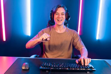 Kazanmak için çevrimiçi oyun oynayan akıllı flama makinesinin sunucu kanalı, neon ışıklı odada seçilen takım yarışması için izleyicilerle birlikte canlı yayında canlı yayında kulaklık takıyor. Bireysel.