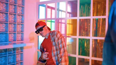 Kafkas dansçısı dans ederken çeşitli arkadaşları gece kulübünde neon ışıkta ayak seslerine bakıyor. Çoklu etnik kökenli hipsterin serbest stil müziğe geçişi ve mutlu bir adamın kameraya bakışıyla. Mutluluk.