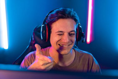 Kazanmak için çevrimiçi oyun oynayan akıllı flama makinesinin sunucu kanalı, neon ışıklı odada seçilen takım yarışması için izleyicilerle birlikte canlı yayında canlı yayında kulaklık takıyor. Bireysel.