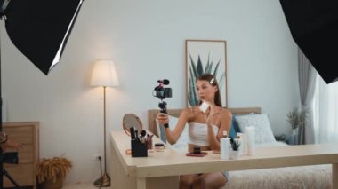 Sosyal medya için güzellik ve kozmetik video içeriği hazırlayan genç bir kadın. Güzellik blogcusu kameraya gülümserken seyircilere ve takipçilere güzellik bakımını gösteriyor. Düzenle