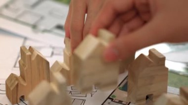 Mimar ve mühendis, mimari belgeyle birlikte masanın üzerine plan yapma, ölçüm araçlarının ofiste etrafa saçılması, ev yerleştirme için ahşap blok kullanımı konularını tartışıyor. - Yakın çekim. Tanımlama.