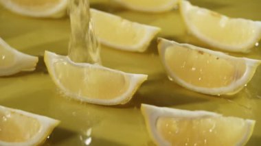 Sarı arka planda suya düşen limon dilimlerinin yukarıdan görünüşü. Taze limon dilimlenmiş, ayrı sarı arka planda su dökülüp sıçrama yapılan yere yakın durun. Citrus tazeliği. Pabulum.