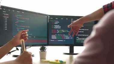 Yavaş çekim arkası yazılım geliştirici mühendisi bilgisayar programlama için birlikte çalışarak hata ayıklama kodunu çözüyor, ofiste monitörde karmaşık algoritmaları çözüyor. Filizlenen