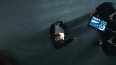 Zeki yöneticinin çeşitli takımlarla tokalaştığı ve tabletteki finansal verileri analiz ettiği yukarıdan aşağıya hava görüntüsü. Kadın lider bir anlaşma yaparak gruba katılıyor ve pazarlama stratejisini paylaşıyor. Müdürlük.