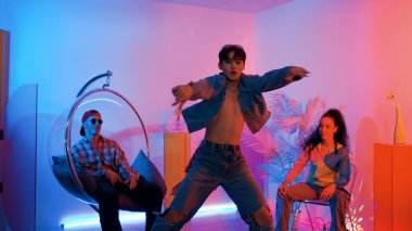 Çok kültürlü bir arkadaş kürsüde otururken Asyalı yetenekli bir dansçı modern müziğe geçiyor. Profesyonel dansçı, hipster takımı tezahürat yaparken ve desteklerken enerjik adımlar atıyor. Mutluluk.