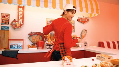 Profesyonel Asyalı restoran işçisi yemek hazırlar ve yemek barının arkasında durur. Kırmızı gömlekli ve kırmızı önlüklü mutlu garson kameraya bakarken serbest stil müziğe geçiyor. Çılgın dans. Mutluluk.