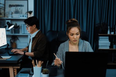 Modern ofiste gece geç saatlerde arka tarafta çalışan iş arkadaşı ile birlikte veri analizi sosyal medya çevrimiçi proje işini rapor etmek için bilgisayara odaklanan iş kadınının ciddi yüzü. İnfobahn.