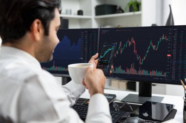 Elinde telefon dinamiğine odaklanan kahve fincanı tutan borsa yatırım ekranı veri analizini karşılaştırarak iç işlerinde yüksek kârlı finans teknolojisi pazarına yatırım yapıyor. Tahmin et..