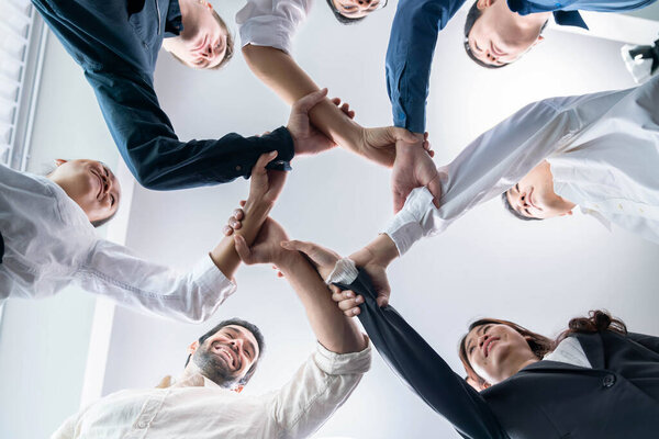 Business team joining hand in circular together symbolize successful group of business partnership and strong collective unity teamwork in diverse culture community workplace. Prudent