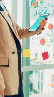 İş adamları ofisteki proje planlama kurulunda çalışıyor ve proje gelişimini analiz etmek için iş arkadaşlarıyla sohbet ediyorlar. Düzenli olması için cam duvara yapıştırılmış yapışkan notlar kullanıyorlar. .