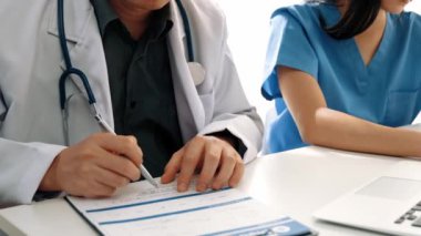 Hastane masasında birlikte çalışan ve tıbbi tedavi planlayan çeşitli profesyonel sağlık görevlileri. Takım çalışması başarılı hastalıklara ve hastalıklara yol açar. Ağır çekim. Katı.