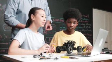 Kafkas öğretmeni dizüstü bilgisayarı işaret ederken araba modelleme sistemini kara tahtada kodlama veya programlama koduyla açıklıyor. Robot inşaatını öğrenen çeşitli öğrencileriniz kutlu olsun. Öğretim