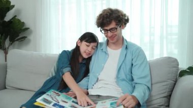 Komik liseli kız masal kitabına işaret ederken mutlu bir baba hikâyesi ve dokunaklı bir jest. Öğrenciler ebeveyn ararken peri kuyruğu hakkında konuşmaktan zevk alırlar. Aile eğlence konsepti. Pedagoji.