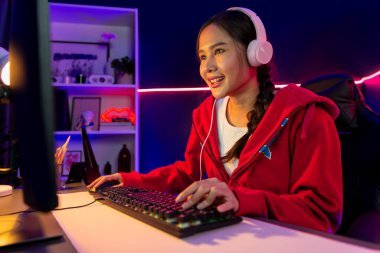 İnternet üzerinden kulaklık takıp gülümseyen Asyalı güzel kız flamasının sunucu kanalı izleyicilerle internet üzerinden konuşma yapıyor. Esport yetenekli takım oyuncuları neon mavi odada. Taktik.