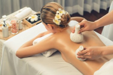 Sıcak bitkisel top spa masaj vücut tedavisi, masör kadın vücuduna nazikçe şifalı bitki torbası bastırıyor. Aromaterapi dinlenme sükuneti ve sükuneti kaplıca salonundaki atmosferi aydınlatıyor. Sessiz.