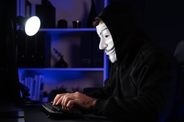 Beyaz gülümseyen isimsiz suçlu maskesi bilgisayar fidye sisteminde veri sunucusuna bilgisayar uygulaması tarafından virüs şifreleme programları yüklüyor. Bilgi bilgisayarda aranıyor. Tahmin et..