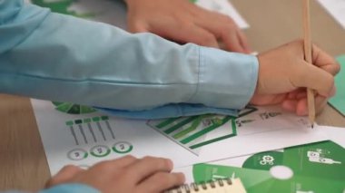 Mükemmel iş adamları, yeşil enerji grafiği kullanımı olan karmaşık bir masada eko ev projesini tartışıyor alternatif enerjiyi seçiyor ya da analiz ediyor, karbonu azaltıp dünyayı kurtarıyor. Eline odaklan. Tanımlama.