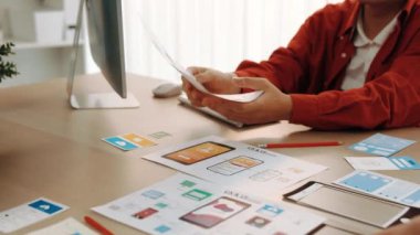 Mobil uygulama için kullanıcı arayüzü prototipini ofis çalışanlarına sunan harika bir şirket çalışanı. UX UI tasarımcısı kağıt üzerinde simge tasarımının işlevini açıklıyor. Sinerjik