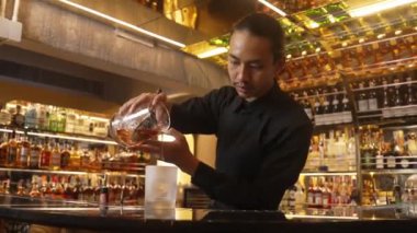 Barmen klasik viski kokteylini sunuyor soğutucu bardağa döküyor lüks içki barında zeki VIP konuğuyla özel hoş geldin içkisi öneriyor. Vinosity.