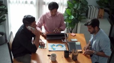 Proje yöneticisi toplantı odasında telefonla konuşurken beyin fırtınası fikriyle birlikte çalışan ekibin üst görüntüsü. Erkek lider yatırımcıyı arıyor ve ekip stratejisini tartışırken mevcut planı sunuyor. Cemaat.