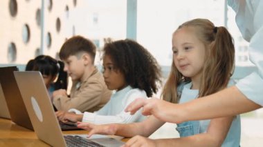 Çok kültürlü bir öğrenci dizüstü bilgisayar kullanarak mühendislik kodları yazarken öğretmen program hakkında açıklama ve öğretim yapıyor. Profesyonel eğitmen BTMM sınıfında programlama sistemini öğrenmeye yardım ediyor. Etkinlik.