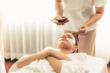 Kaplıca salonunun sakin atmosferi, kadın müşteri modern gün ışığında lüks yüz kremi masajıyla kendini yenileme zevkine kapılıyor. Yüz bakımı ve güzellik konsepti. Sessiz.