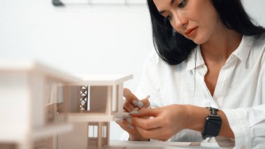 Closeup portrait image of professional young beautiful engineer architect using triangular scale measures house model with focusing at modern office. Business creative design concept. Immaculate. clipart