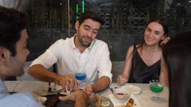 Grup arkadaşı ya da çift, ızgarada ve ana yemek masasında yemek yerken akıllı telefonla konuşuyor. Lüks restoranda etkileyici bir dostluk ortamında tanışma teması. Vinosity.