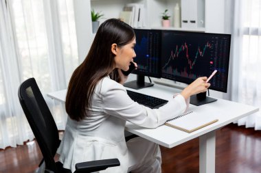 Genç ve güzel Asyalı iş kadını komisyoncuya sesleniyor, bilgisayar piyasasındaki artan döviz piyasasındaki kalemle modern ofise yüksek kârlı yatırım yapmak ve zenginliğe yüksek kazanç sağlamak için işaret ediyor. Taktik.