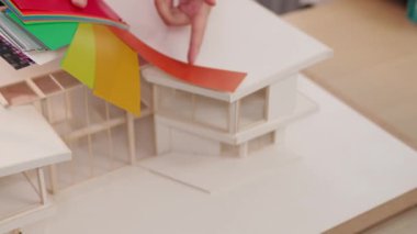 Mimari ekipman kullanarak yavaş çekim ev tasarımcısı bir plan çizerken, iç mimari tasarımcı da müşterilerin talebine göre renk örneklerinden uygun renkler seçiyor. Değiştirilmiş