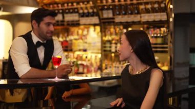 Barmen çiçekle süslenmiş karışık votka servisi yapıyor. Güzel bir konukla tezahürat yapıyor. Lüks tezgah barında oturuyor. Vinosity.