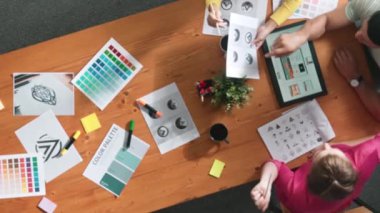 Proje yöneticisi renk paletleri seçerken tasarımcının tablete baktığı yukarıdan aşağıya hava görüntüsü. Profesyonel grafik tasarımının en üst görüntüsü ve logoya bakın. Yetenekli ekip grafikleri seçiyor. Sempozyum.