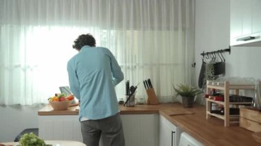 Mutlu baba yemek pişirirken müziğe geçiyor ve modern mutfakta öğle yemeği hazırlıyor. Aktif baba, sebze ve mutfak gereçleri ile çevrili sağlıklı yemek ya da salata yaparken şarkıyla dans ediyor. Pedagoji.