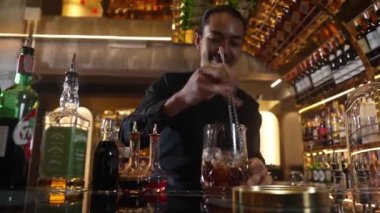 Zeki Asyalı barmen bardakta karıştırılmış alkol şurubunu buzla karıştırıyor. Çünkü kayanın üzerinde kamera var. Gece kulübünde taze kokteyl kokteylleri karıştırıyor. Vinosity.