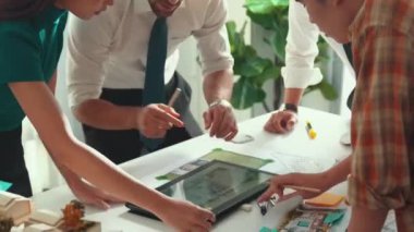 Akıllı iş adamlarının tasarımı planlamak için tabletten proje planına bakarken ve planlar ve toplantı masasındaki bina inşaatı hakkında tartışırken birlikte çalışması. Hizalama.