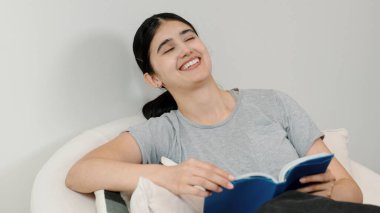 Kanepede oturan orta yaşlı bir kadın, sosyal ve teknolojik mesleki gelişmeler hakkında ders kitabı okur ya da zeki bir anne olmak için çocuk yetiştirir. Hayat boyu öğrenme konsepti. Uyumsuzluk.