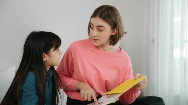 Beyaz bir anne, tatlı kızının dinlediği hikayeleri okuyor. Asyalı kız yatmadan önce hikâyeyi anlatırken işaret etti. Birlikte vakit geçirirken mutlu bir aile yatakta oturuyor. Pedagoji.