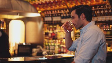 Profilde, beyaz tişörtlü, gülümseyen zeki bir adamın cuma gecesi lüks bir barda özel parti içeceği kokteylinden kokteyl içtiği görülüyor. Vinosity.