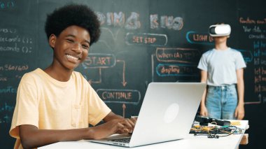 Smart african student programing and coding innovative system while caucasian girl enter in metaverse or virtual world by using VR or head set at blackboard in STEM technology classroom. Edification. clipart