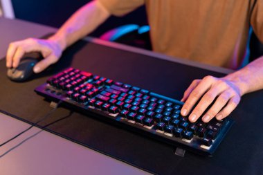 Bilgisayardaki klavye ve neon mavi ve pembe ışıklandırma siberinin faresiyle oynanan oyun odaklı ellerin yaratıcı görüntüsü. Takım yeteneğine sahip çok oyunculu oyun flaması kavramı. Bireysel.