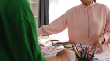 Yavaş çekim iki tasarımcı beyin fırtınası yapıyor ve grafik tasarımı için renk seçiyor ya da istemci renk bozukluklarını tasarımcı bürosundaki kromatik konsültasyonla karşılaştırıyor. Değiştirilmiş