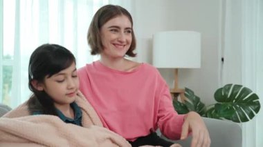 Kafkasyalı anne enerjik kızını sıcak bir battaniyeyle örtüyor. Mutlu anne evinde kanepede otururken akıllı öğrencisini battaniyeye sardı. Sevgi ve şefkat göstergesi. Pedagoji.