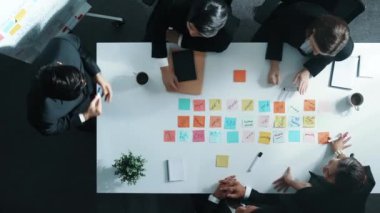 İş adamlarının yukarıdan aşağıya hava görüntüsü proje yöneticisine satışları bildirirken, başlangıç ekibi toplantı odasında artan karı kutlamak için el çırpıyor. Bir grup yönetici bir çözüm buluyor. Müdürlük.