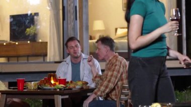 Anne ve büyükanne, aile üyeleri yıldönümü kutlamalarında yemek yerken ızgara yapıyor. Güzel akrabalarla vakit geçirmek için açık hava kamp aktiviteleri kuşaklar arası fark yaratır. Uyumsuzluk.