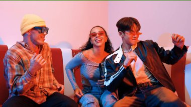 Mutlu kız kameraya bakıyor ve kanepede otururken pop müzik dinliyor. İspanyol kadın serbest stil dans ederken kameraya bakıyor neon ışıkta çeşitli arkadaşlarla dans ediyor. Mutluluk.